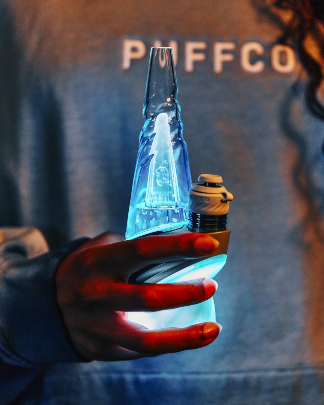 Close-up of the Puffco Peak Pro Glacier glowing blue in hand